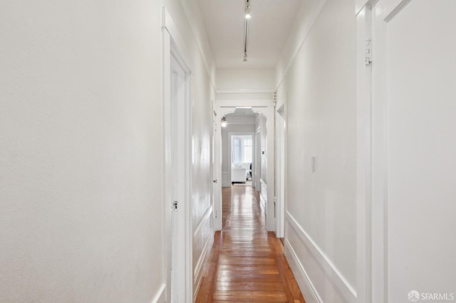 hallway featuring track lighting, ornamental molding, and wood-type flooring