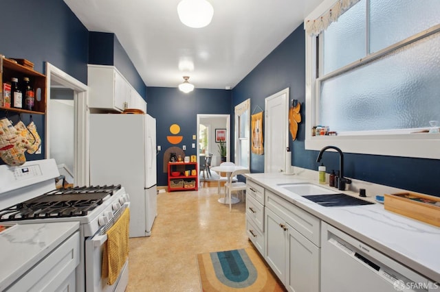 kitchen featuring white appliances, white cabinetry, light stone counters, and sink