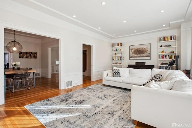 living room with built in features and hardwood / wood-style floors