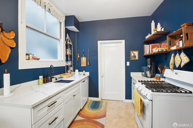 kitchen with sink, white appliances, white cabinets, and light stone countertops