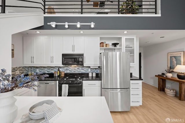 kitchen with white cabinets, decorative backsplash, light wood-type flooring, and appliances with stainless steel finishes