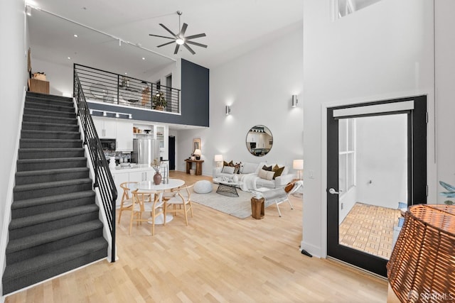 living room featuring a high ceiling, ceiling fan, and light hardwood / wood-style floors