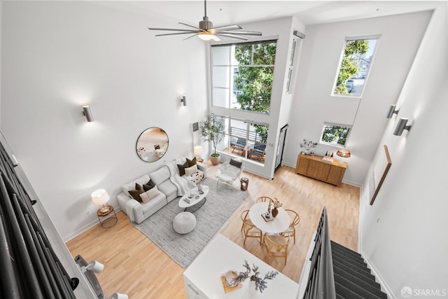 living room featuring a high ceiling, ceiling fan, and hardwood / wood-style flooring