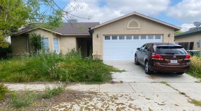 ranch-style home with a garage, stucco siding, and driveway
