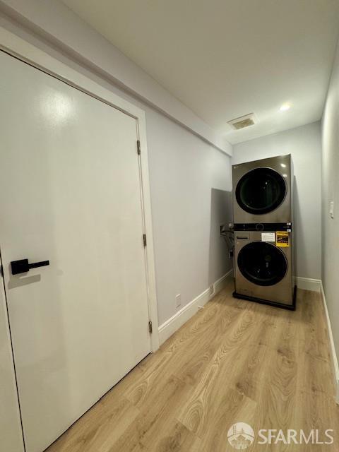 672 Prentiss St, San Francisco, CA 94110 - laundry area featuring estacked washer and dryer, light wood-style flooring, and baseboards