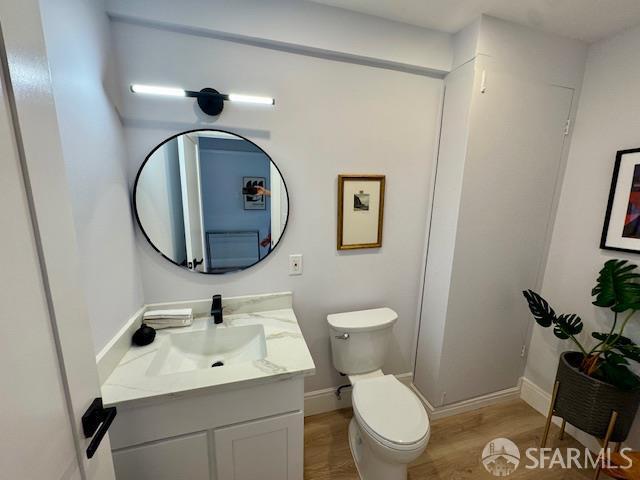 672 Prentiss St, San Francisco, CA 94110 - bathroom with vanity, toilet, wood finished floors, and baseboards