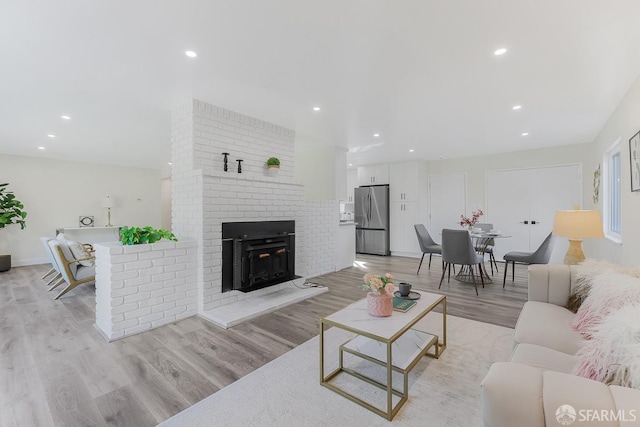 living room featuring light hardwood / wood-style floors and a brick fireplace