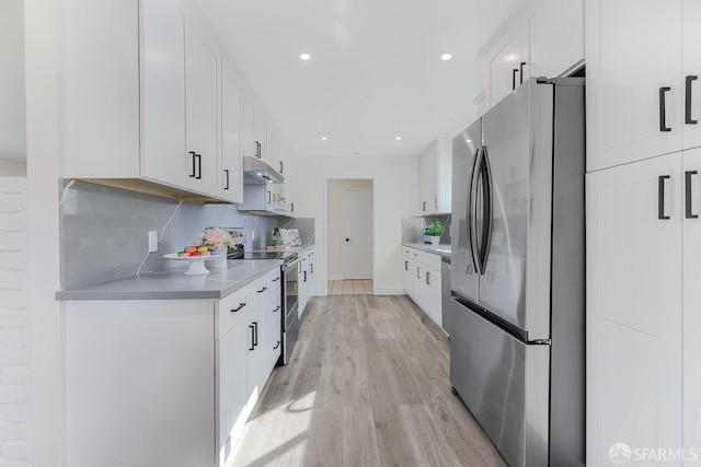 kitchen featuring white cabinets, decorative backsplash, stainless steel appliances, and light hardwood / wood-style flooring