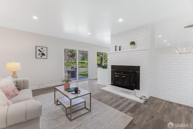 living room with wood-type flooring and a brick fireplace