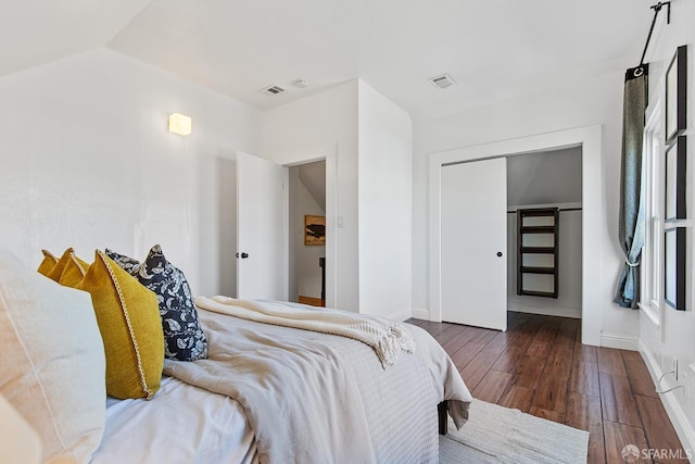 bedroom with visible vents, wood-type flooring, baseboards, and vaulted ceiling