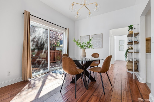 dining space featuring baseboards, an inviting chandelier, and wood finished floors