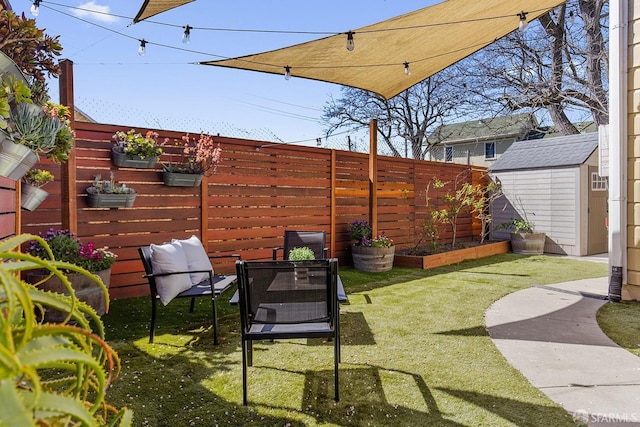 view of yard featuring an outdoor structure, a storage shed, a fenced backyard, and a garden