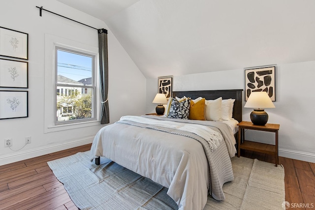 bedroom with baseboards, wood finished floors, and vaulted ceiling