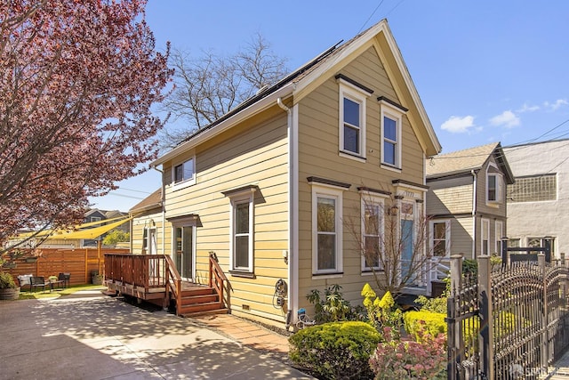 view of front of home with a patio area, a wooden deck, a gate, and fence