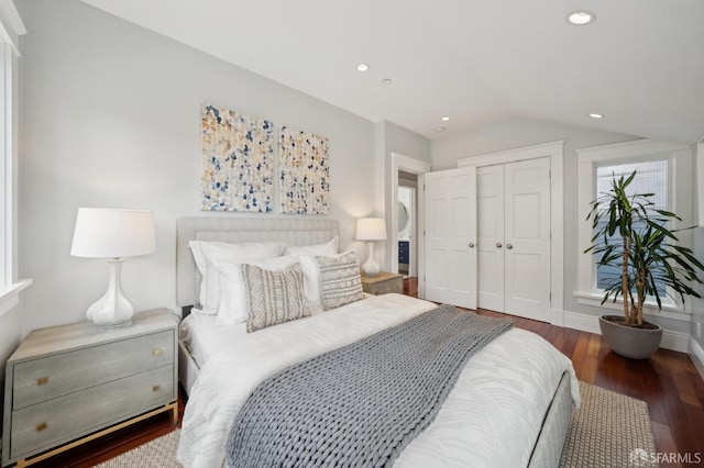 bedroom with a closet, vaulted ceiling, and dark hardwood / wood-style floors