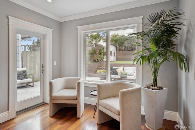 living area with hardwood / wood-style flooring, ornamental molding, and a healthy amount of sunlight