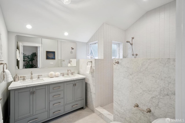 bathroom featuring a tile shower, vanity, tile patterned flooring, and vaulted ceiling