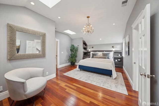 bedroom featuring a notable chandelier, wood-type flooring, and vaulted ceiling with skylight