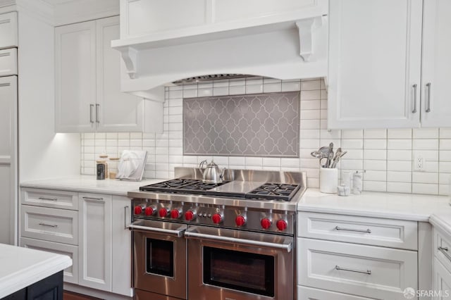 kitchen with white cabinetry, backsplash, custom exhaust hood, and range with two ovens