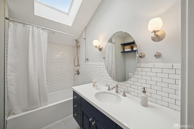 bathroom featuring shower / bath combo, tile walls, vaulted ceiling with skylight, vanity, and tile patterned floors