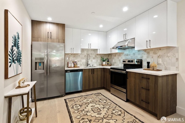 kitchen featuring dark brown cabinets, sink, white cabinets, light hardwood / wood-style floors, and stainless steel appliances