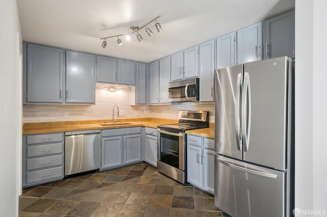 550 S Van Ness Ave Unit 306, San Francisco, CA 94110 - kitchen featuring appliances with stainless steel finishes, gray cabinetry, stone finish flooring, and tasteful backsplash