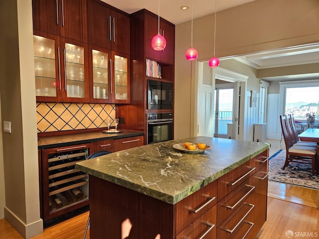 kitchen featuring beverage cooler, tasteful backsplash, a kitchen island, black appliances, and light wood-type flooring