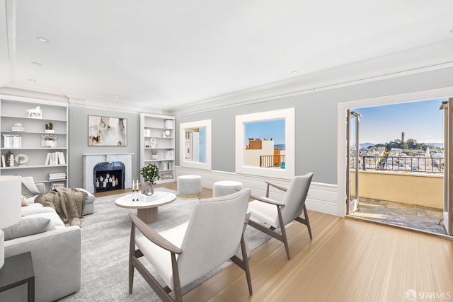 living room with crown molding, built in features, and light hardwood / wood-style floors