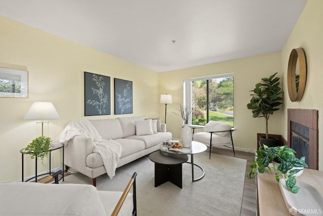 living area featuring a glass covered fireplace, baseboards, and wood finished floors
