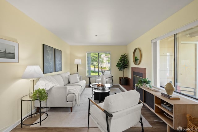 living room with a tile fireplace, baseboards, and wood finished floors