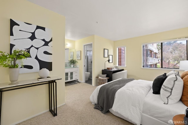carpeted bedroom featuring baseboards and ensuite bathroom