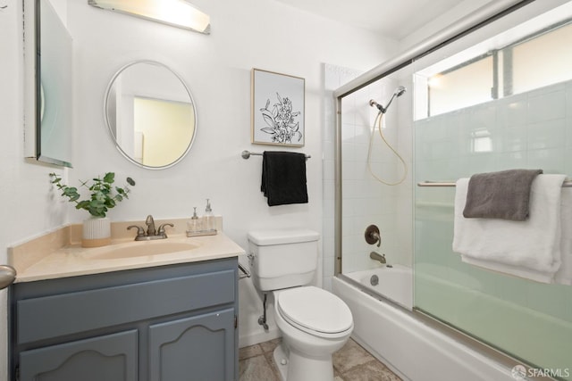 bathroom with baseboards, toilet, vanity, and combined bath / shower with glass door