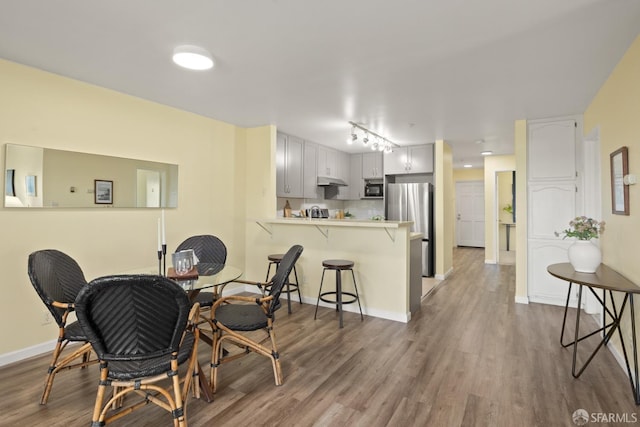dining area featuring track lighting, baseboards, and wood finished floors