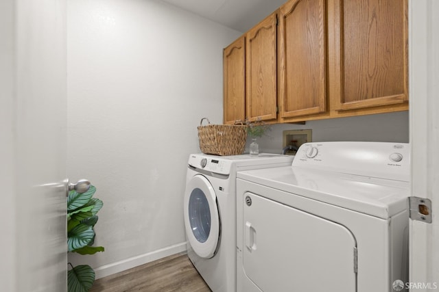 laundry area featuring cabinet space, light wood-style floors, baseboards, and separate washer and dryer