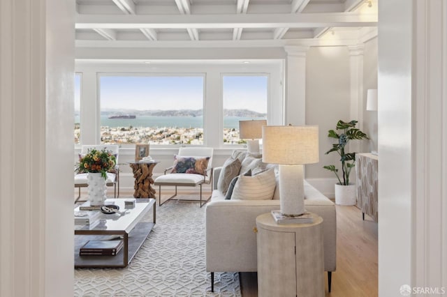 living area with beam ceiling, wood finished floors, a water view, and coffered ceiling