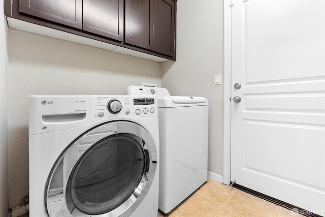 washroom featuring baseboards, cabinet space, washing machine and clothes dryer, and light tile patterned floors