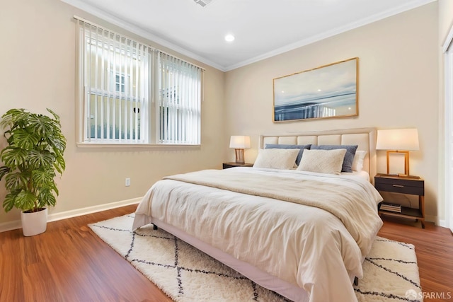 bedroom with ornamental molding, baseboards, and wood finished floors