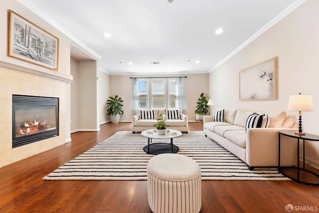 living room featuring ornamental molding, visible vents, a fireplace, and wood finished floors