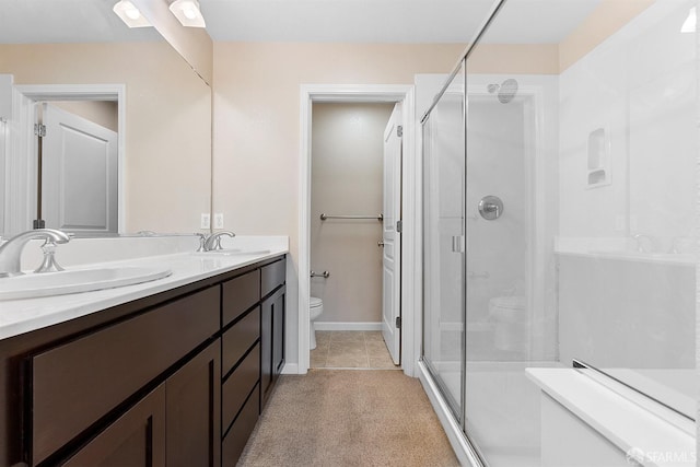 full bath with toilet, a shower stall, double vanity, and a sink