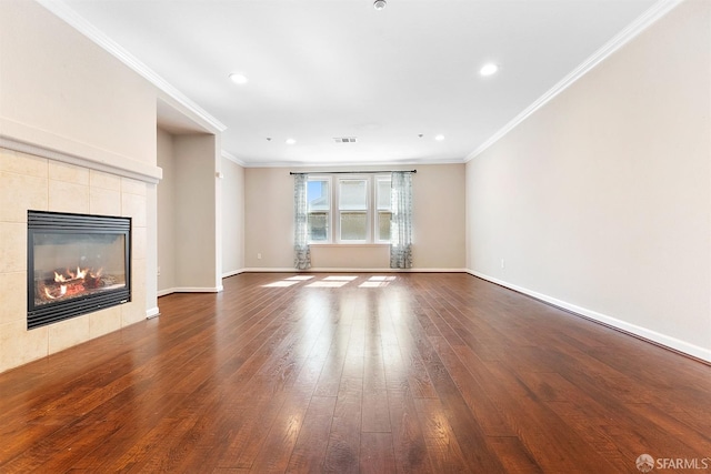 unfurnished living room with dark wood-style flooring, a tiled fireplace, and crown molding