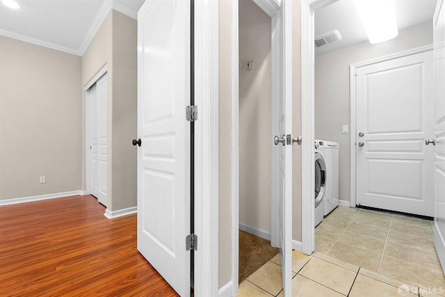 laundry room featuring light tile patterned floors, ornamental molding, washer / dryer, laundry area, and baseboards