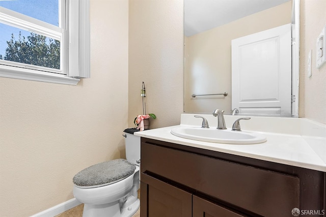 bathroom with toilet, vanity, and baseboards