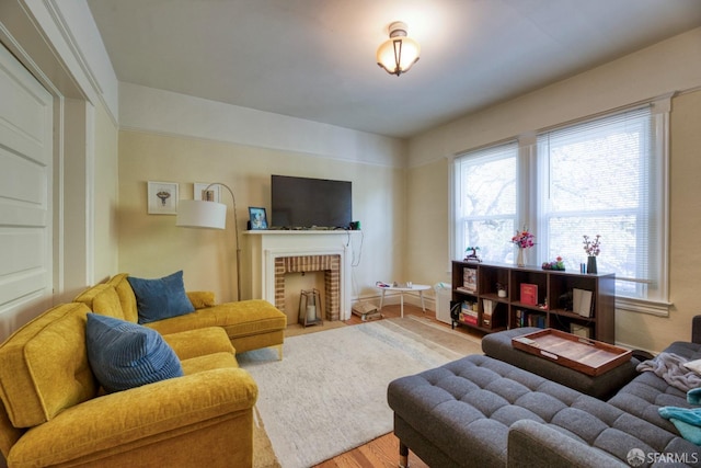 living room featuring a brick fireplace and light wood-type flooring