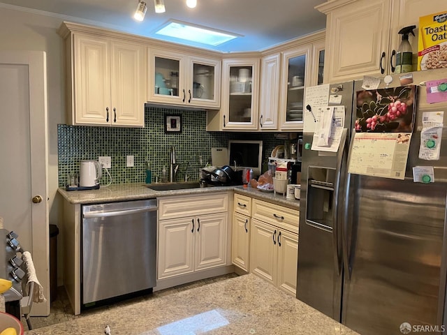 kitchen with tasteful backsplash, stainless steel appliances, sink, and cream cabinetry