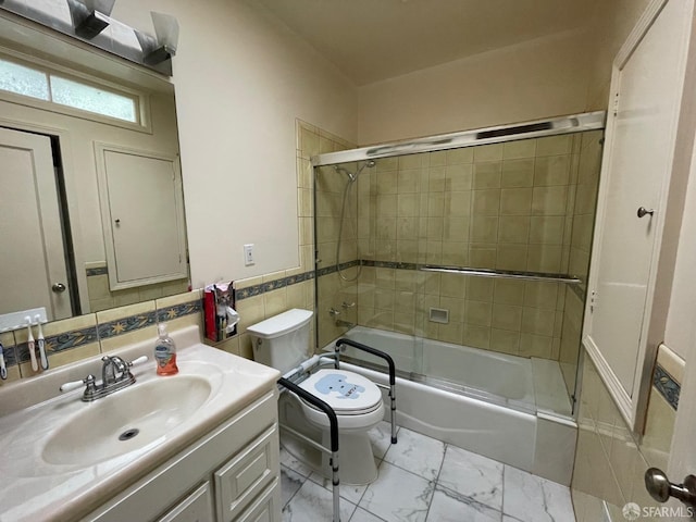 full bathroom with vanity, toilet, tile walls, and bath / shower combo with glass door