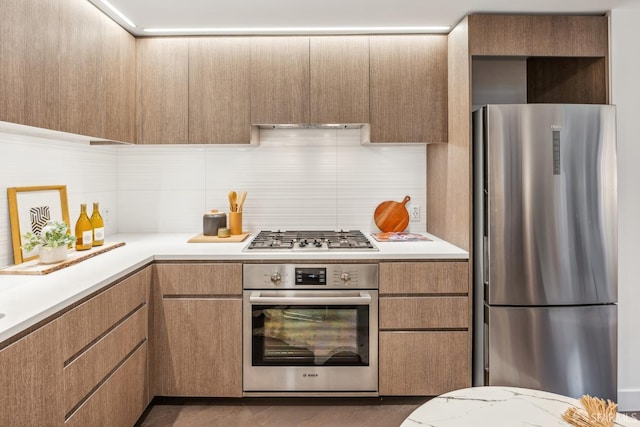 kitchen with dark hardwood / wood-style flooring, exhaust hood, appliances with stainless steel finishes, and tasteful backsplash