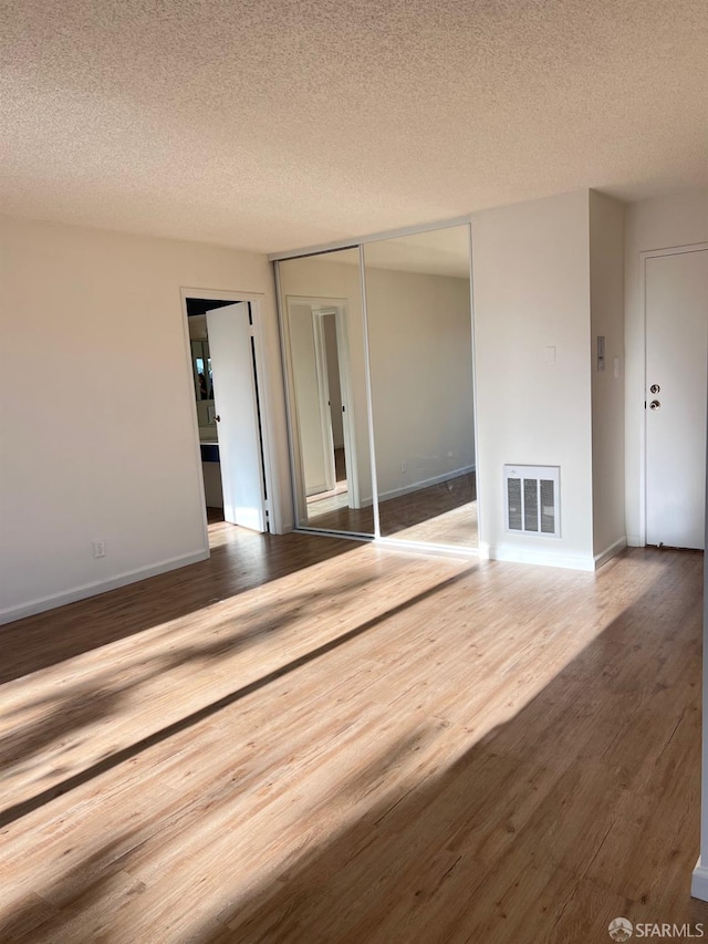 unfurnished living room featuring hardwood / wood-style floors and a textured ceiling