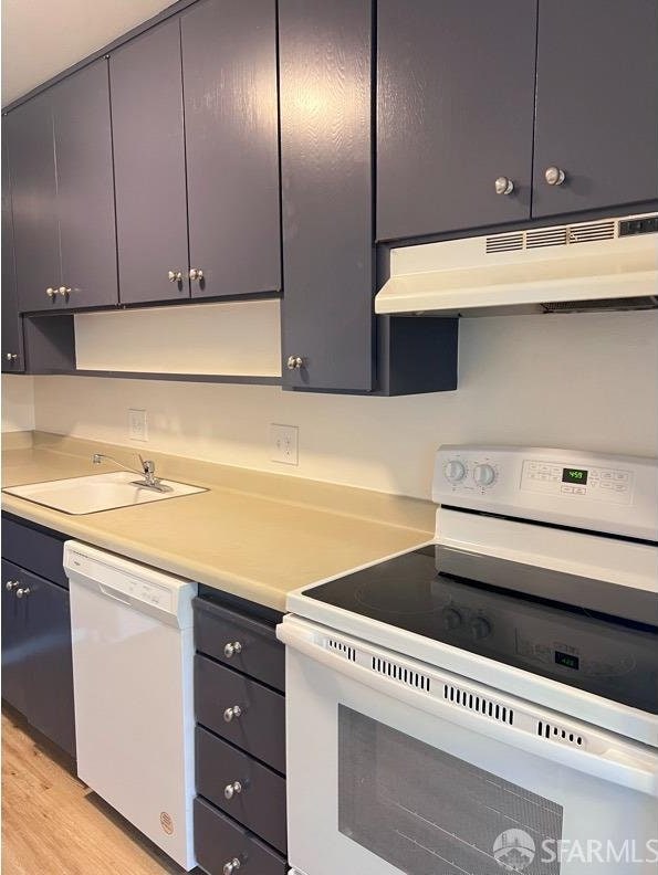 kitchen with white appliances, light hardwood / wood-style floors, and sink