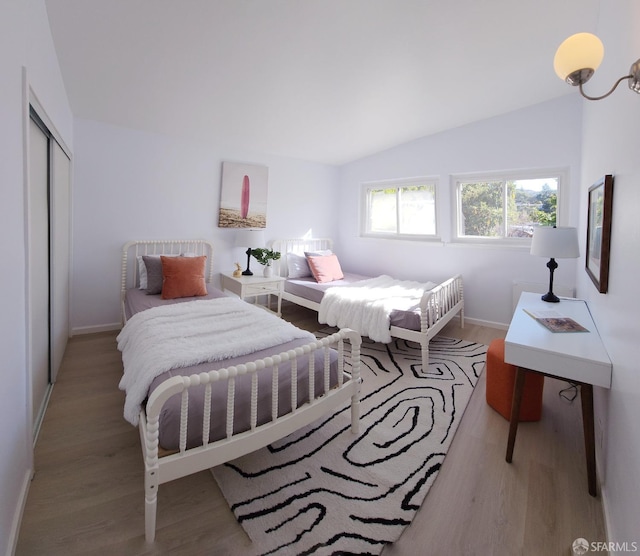 bedroom with light hardwood / wood-style flooring, a closet, and lofted ceiling