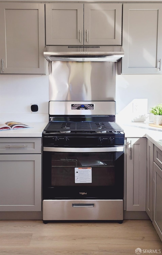 kitchen featuring gas stove, light wood-type flooring, and gray cabinetry